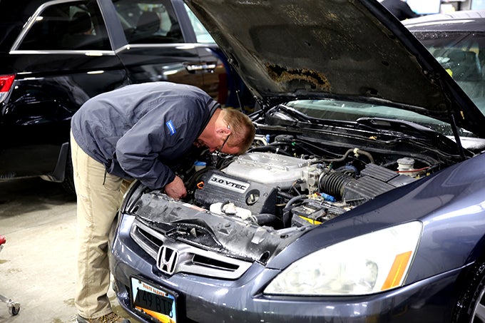 Grand forks service technician inspecting engine of car during service appointment